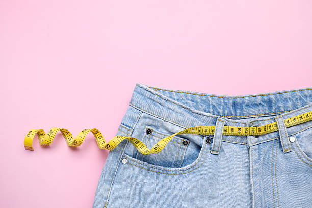 istock Jeans and measuring tape on pink background, top view 2211724439