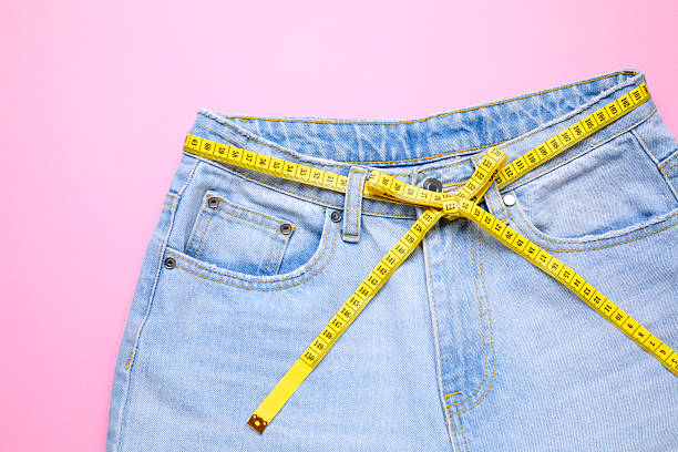 istock Jeans and measuring tape on pink background, top view 2211724447