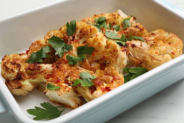 istock Tasty cauliflower steaks and parsley in baking dish on white table, closeup 2211724698