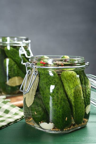istock Making pickles. Fresh cucumbers and spices in jars on wooden table 2211724959