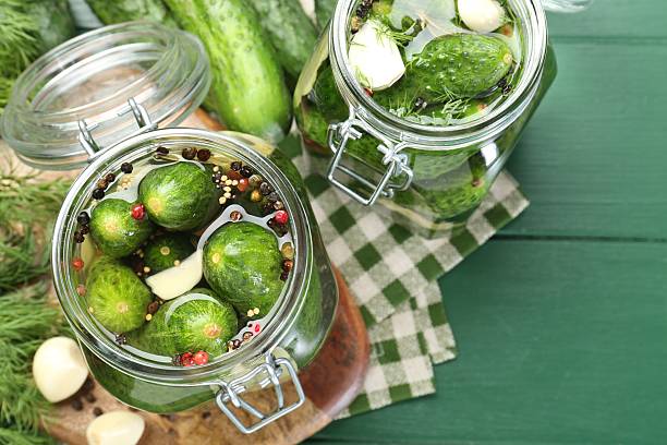 istock Making pickles. Fresh cucumbers and spices in jars on wooden table, flat lay 2211724981