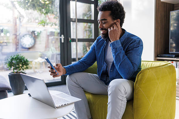istock Man using smartphone and laptop while sitting in a modern living room 2211725091