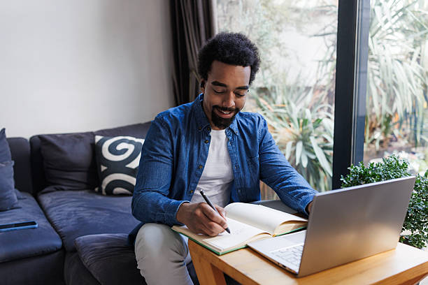 istock Man studying with a laptop and notebook in a cozy home environment 2211725103