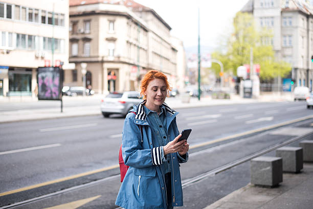 istock Young woman using phone standing at the street 2211727075