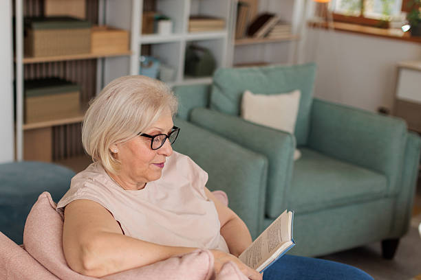 istock Senior woman reading a book at home 2211734861