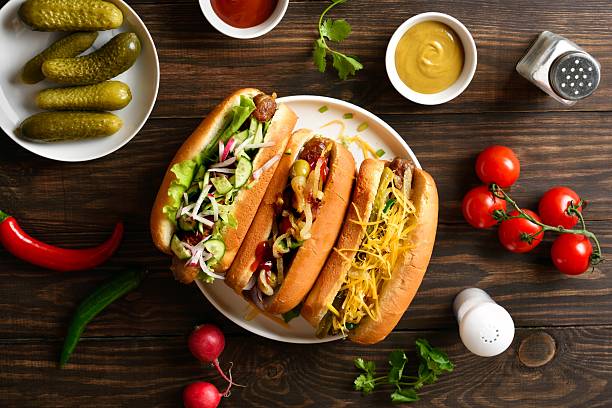 istock Hot dogs loaded with assorted toppings on wooden background 2211735720