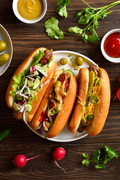 istock Hot dogs loaded with assorted toppings on wooden table 2211735728