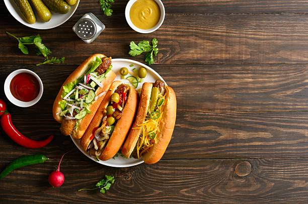 istock Hot dogs loaded with assorted toppings on wooden background 2211736431