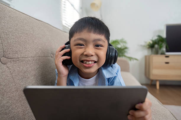 istock Back to School and Learning Fun. A joyful boy with headphones, showcasing excitement while using a tablet. 2211737938