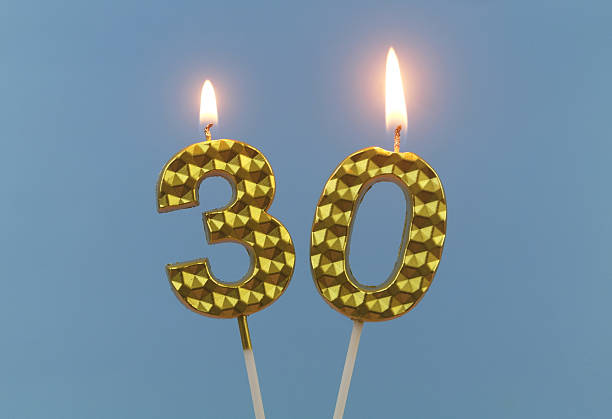 istock Gold birthday candles burning on blue, number 30. 2211738184