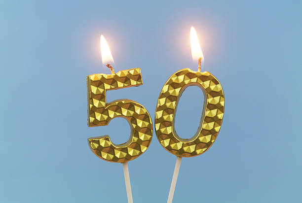 istock Gold birthday candles burning on blue, number 50. 2211738344