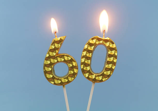 istock Gold birthday candles burning on blue, number 60. 2211738351