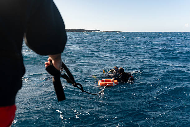 istock Dive instructor assisting divers at sea with floating safety equipment 2211738496
