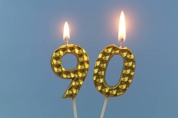 istock Gold birthday candles burning on blue, number 90. 2211738575