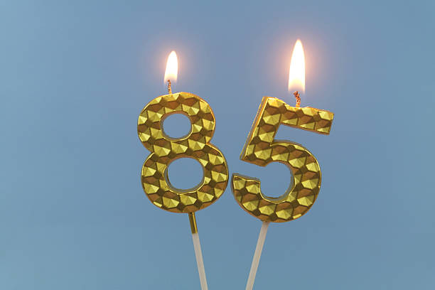 istock Gold birthday candle burning on blue, number 85. 2211739294