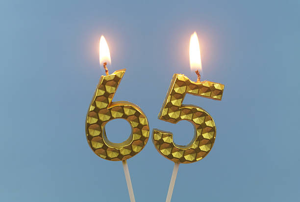 istock Gold birthday candle burning on blue, number 65. 2211739593