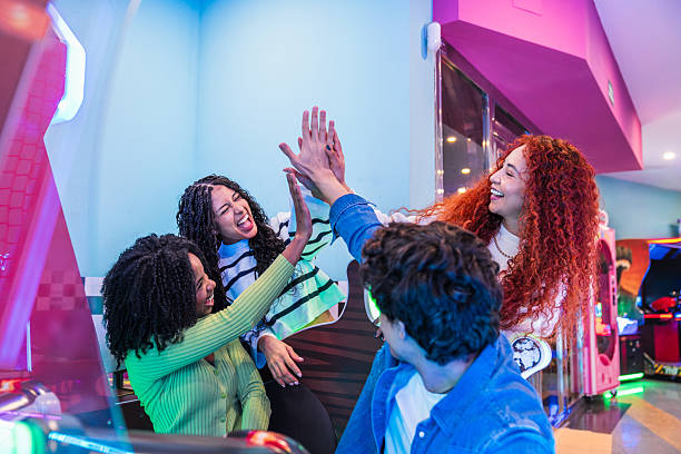 istock Enthusiastic friends giving high five while playing in the arcade 2211740762