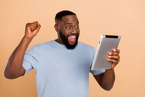 istock Portrait of attractive cheerful lucky guy using device gadget rejoicing having fun isolated over beige pastel color background 2211742229