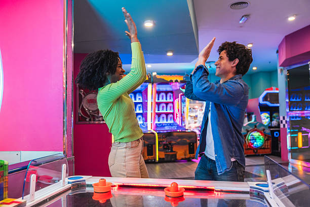 istock Friends giving high five while playing air hockey in an arcade 2211742457