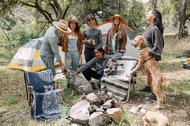 A multi ethnic group of friends laughing and relaxing in a natural outdoor setting. Camping with tent.