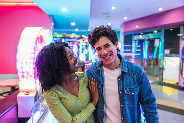istock Young couple having fun playing in a colorful arcade videogame room 2211743169