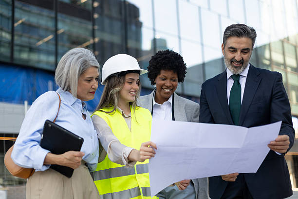 istock Architects and engineers examining blueprint in front of modern building 2211746397