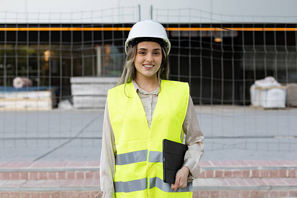istock Female engineer smiling and holding tablet at construction site 2211746415