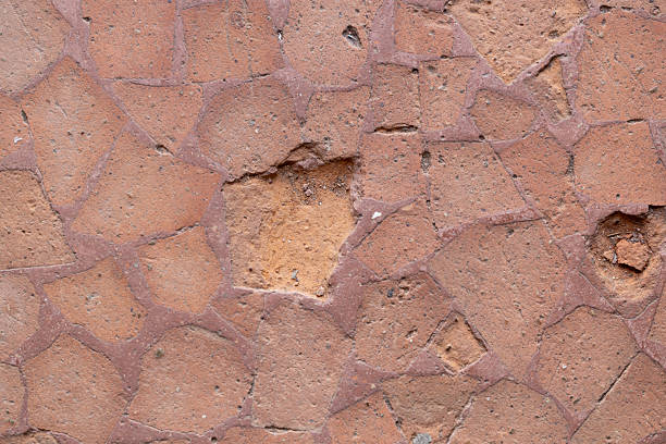 Worn mosaic floor made of reddish terracotta tiles with visible cracks and missing pieces in an aged texture.
