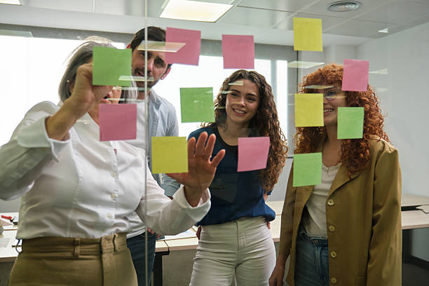 istock Business team brainstorming with sticky notes on glass wall in office 2211747872