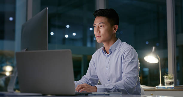 istock Business, laptop and man with computer in office at night for software development, troubleshooting or coding deadline. Web developer, employee and typing on technology for system update or UI design 2211750664
