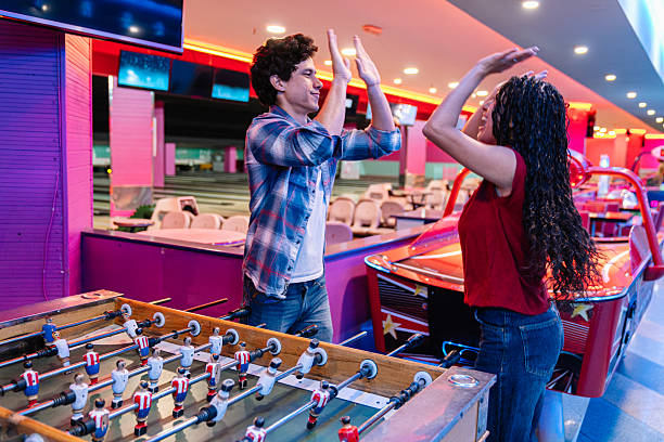istock Friends giving high five while playing foosball in bowling alley 2211753014