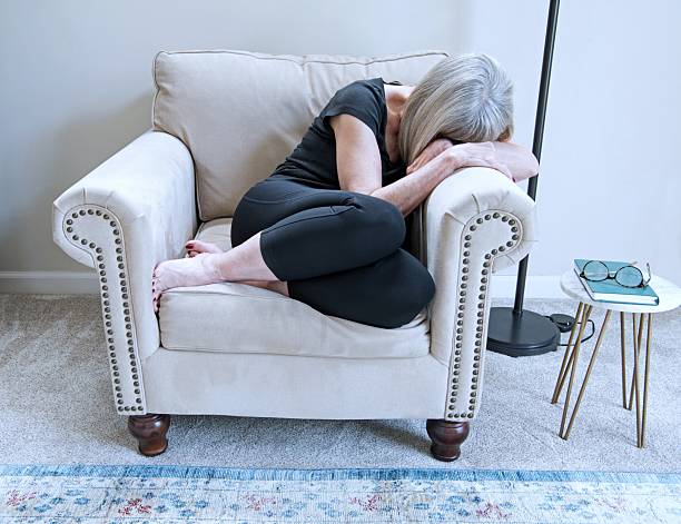 Woman Curled up, Sleeping in Upholstered Chair stock photo