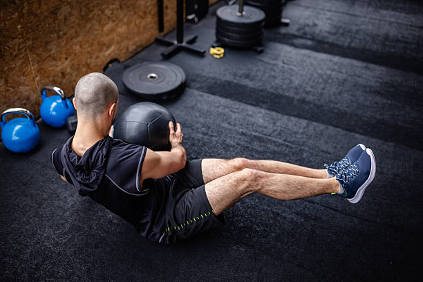 istock Young man focuses on strength training with a medicine ball in a modern gym setting 2211756589