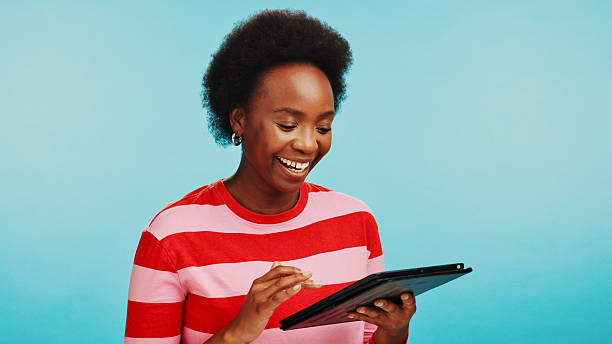 istock Studio, black woman and happy with tablet for education results, academy mark and scroll for good news. Mockup, female person and student with tech for college acceptance, excited and blue background 2211759312