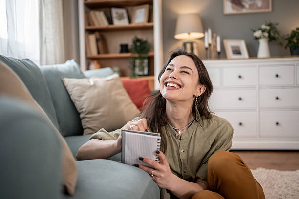istock Young woman smiling and taking notes in her living room 2211760402