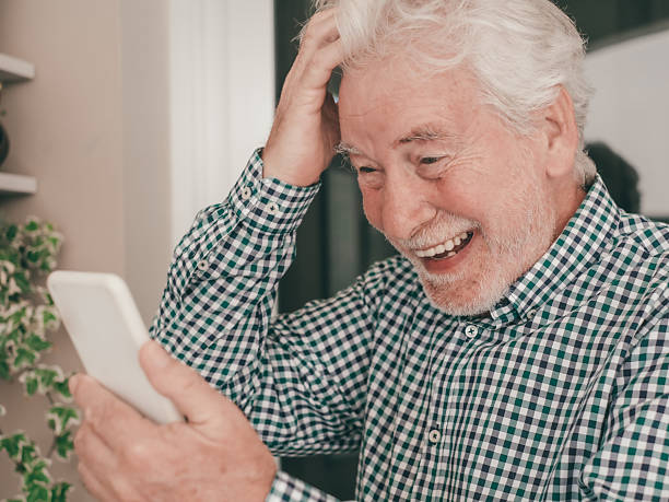 istock Happy Video Call. Heart-Warming Connections for a smiling senior bearded grandfather using smartphone to stay in touch with distant family or friend 2211760830