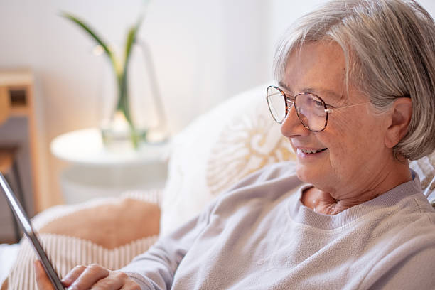 istock Smiling relaxed senior woman lying in bed using a digital tablet communicating in remote chat with family or browsing internet 2211769301