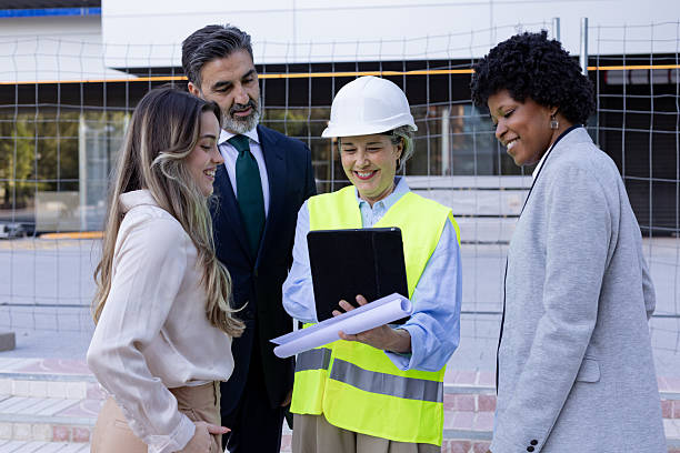 istock Architect showing tablet and blueprint to businesspeople at construction site 2211770914