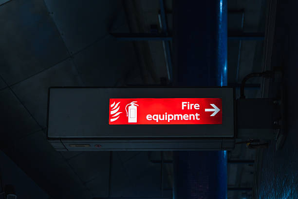 istock Illuminated Fire Equipment Sign with Arrow in Dark Indoor Industrial Setting 2211771886