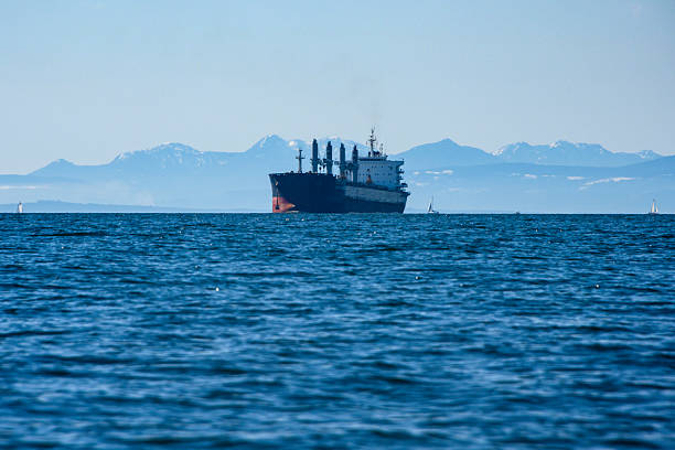 istock Cargo ship navigates calm waters near snow-capped mountains on a clear day 2211772290