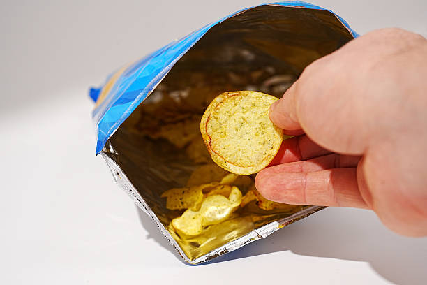 istock potato chips in hand. potato chips with spices in a packet. 2211778189
