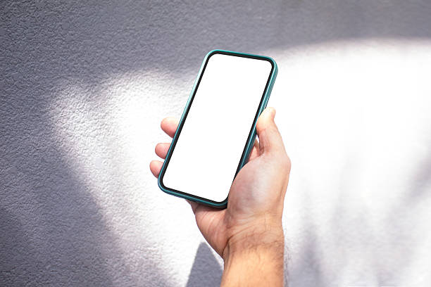 istock Man holding phone blank outdoor with organic drop shadow on a white wall 2211780754