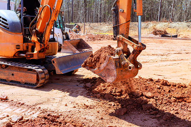 istock Excavator digging soil at a construction site during daytime in a forested area 2211782116