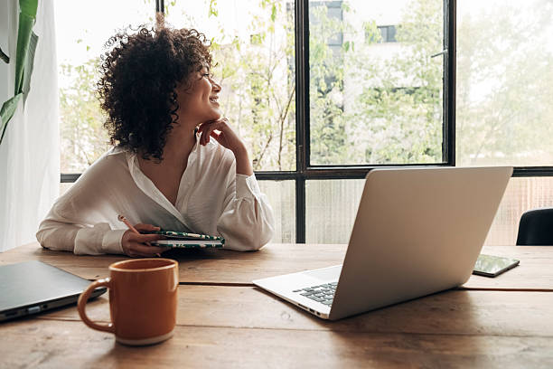 istock Young woman taking a break from work, looking out the window 2211782200
