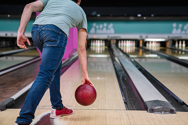 istock Man bowling, throwing ball down alley in bowling hall 2211782524