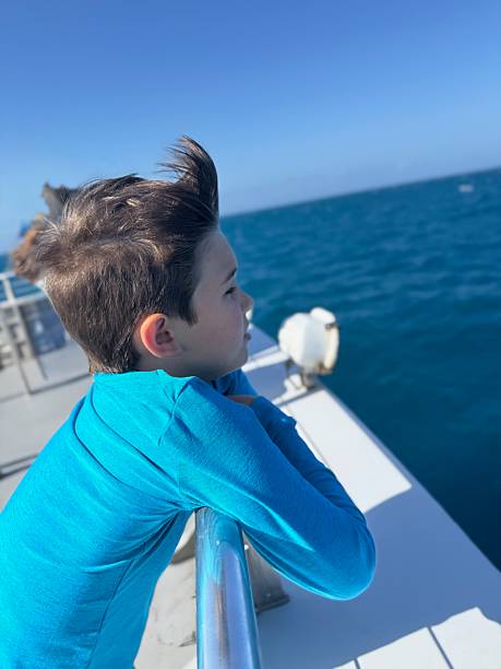 Boy on boat looking out at sea, day dreaming