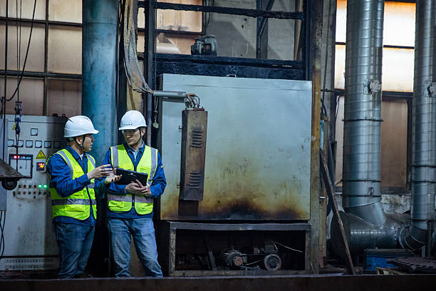 Two Asian workers discussing work in heat treatment workshop
