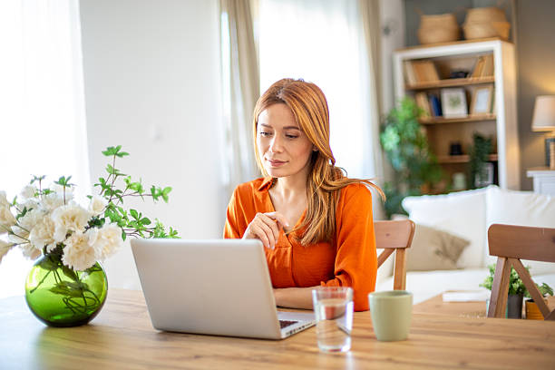 istock Focused young woman working from home on laptop at dining table 2211784453