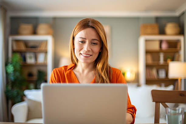 istock Smiling woman working from home on laptop computer 2211785080