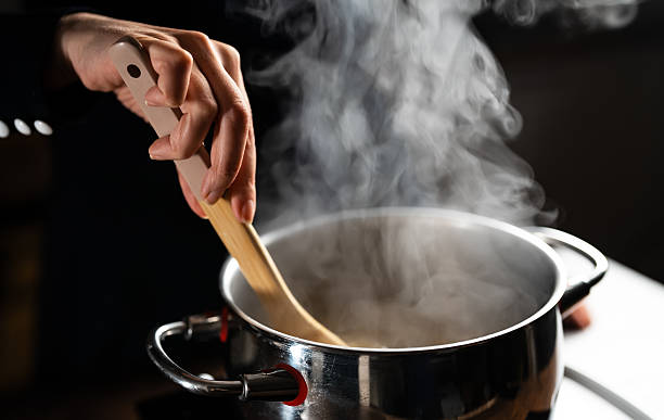 istock Female chef cooking with steam rising from pot. 2211787683